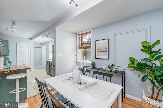 dining room with light hardwood / wood-style flooring and rail lighting