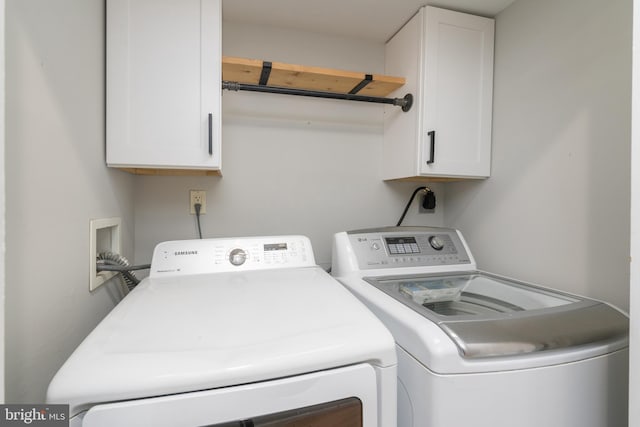 laundry room with separate washer and dryer and cabinets