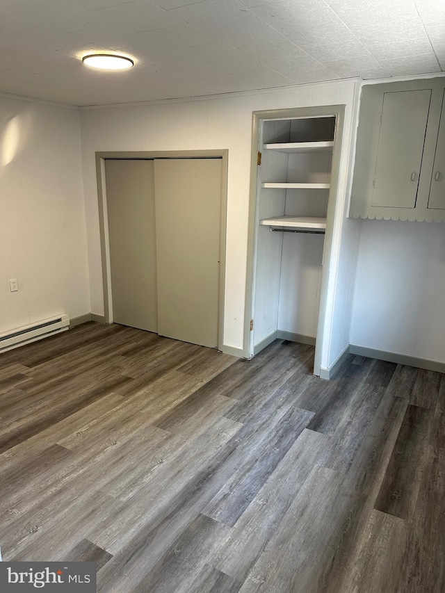 unfurnished bedroom with wood-type flooring and a baseboard radiator