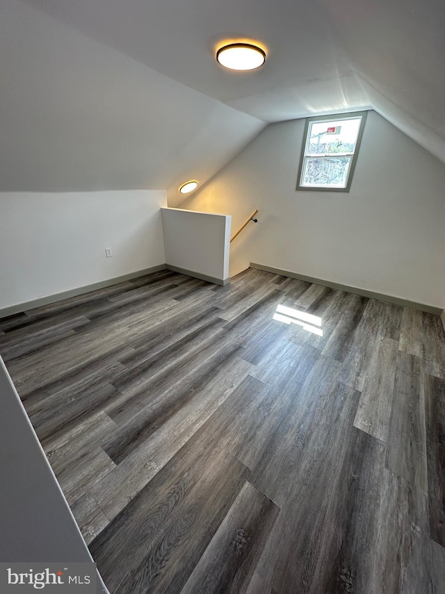 additional living space with vaulted ceiling and dark wood-type flooring