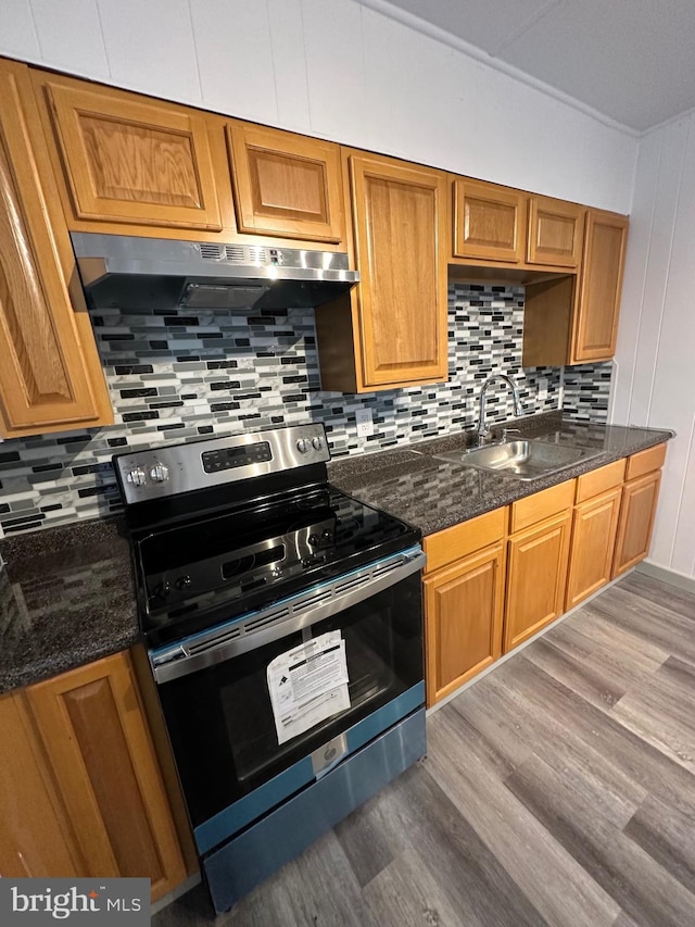 kitchen featuring stainless steel electric range, dark stone counters, sink, and light hardwood / wood-style floors