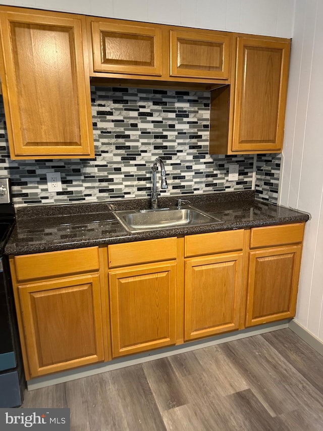 kitchen with stainless steel electric range oven, tasteful backsplash, dark hardwood / wood-style flooring, dark stone countertops, and sink