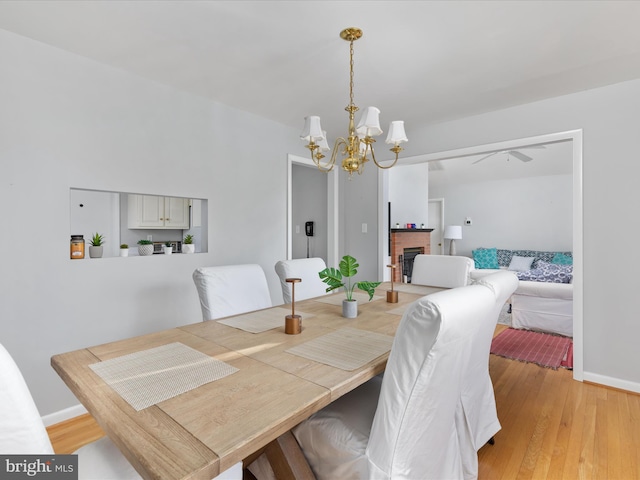 dining space featuring light hardwood / wood-style floors, an inviting chandelier, and a fireplace