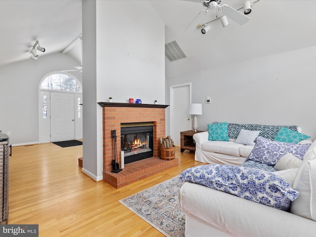 living room featuring hardwood / wood-style flooring, a brick fireplace, ceiling fan, and vaulted ceiling