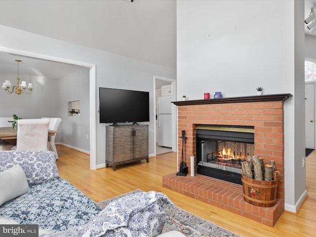 living room with a fireplace, an inviting chandelier, and light hardwood / wood-style flooring