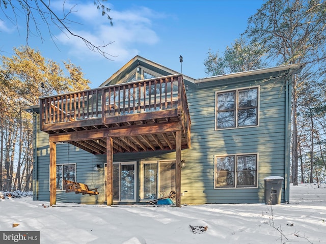 snow covered back of property with a deck