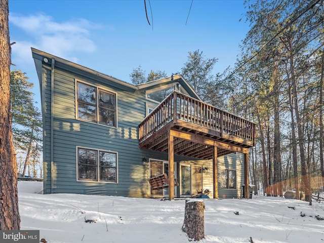 snow covered rear of property with a wooden deck