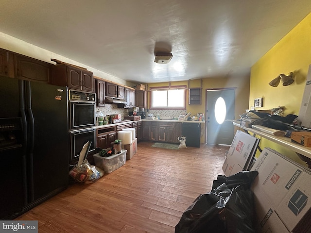 kitchen with black appliances, light hardwood / wood-style flooring, decorative backsplash, and dark brown cabinetry