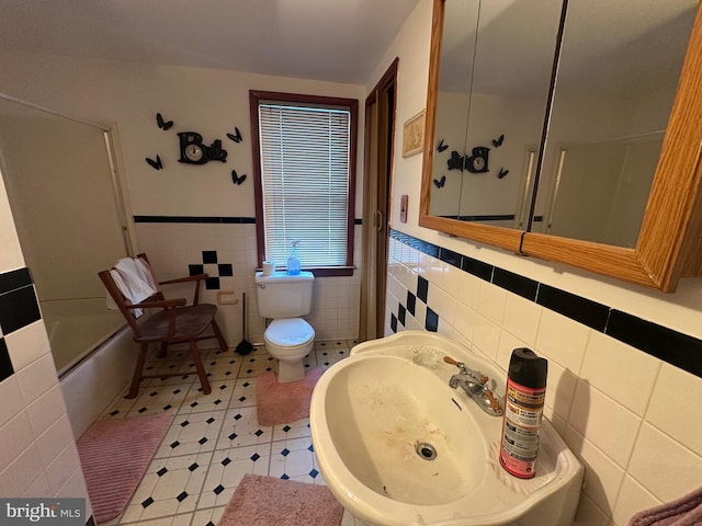 full bathroom with tile patterned floors, washtub / shower combination, sink, tile walls, and toilet