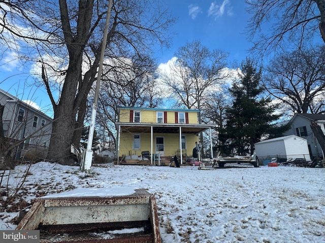 snow covered house featuring a porch