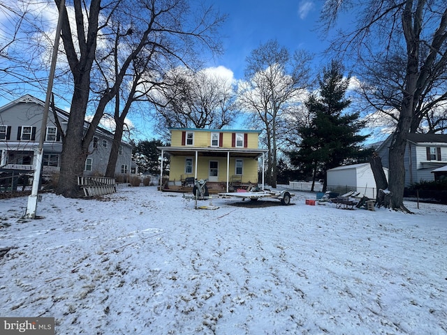 snow covered rear of property with covered porch