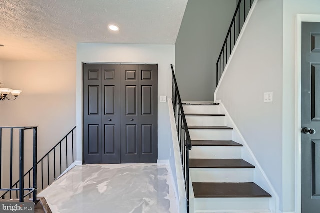 stairs featuring a notable chandelier and a textured ceiling