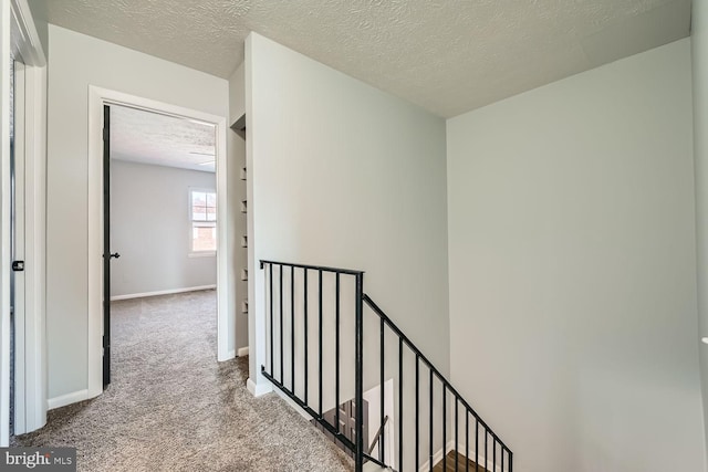 hallway featuring light colored carpet and a textured ceiling