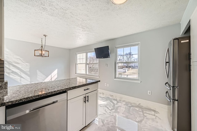 kitchen featuring decorative light fixtures, white cabinetry, dark stone counters, stainless steel appliances, and a textured ceiling