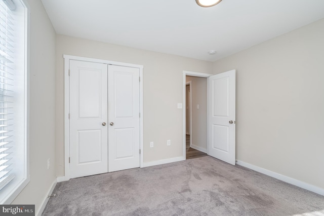 unfurnished bedroom with a closet and light colored carpet