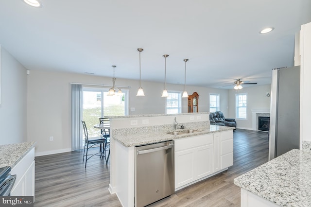 kitchen with white cabinetry, stainless steel appliances, a kitchen island with sink, decorative light fixtures, and sink