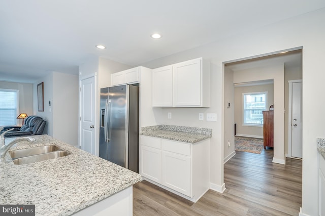 kitchen with stainless steel fridge with ice dispenser, white cabinetry, and light stone countertops