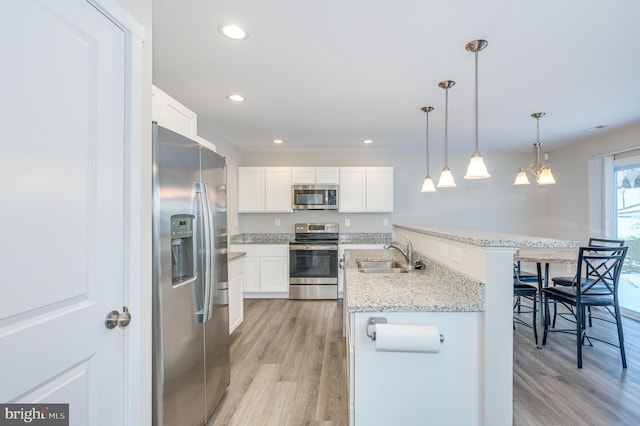 kitchen featuring pendant lighting, white cabinetry, stainless steel appliances, sink, and a breakfast bar