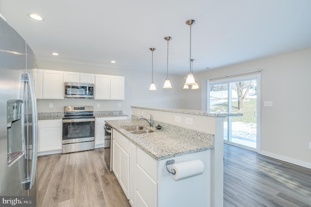 kitchen featuring appliances with stainless steel finishes, white cabinetry, hanging light fixtures, and sink