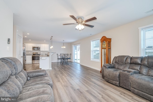 living room featuring ceiling fan, light hardwood / wood-style flooring, and sink