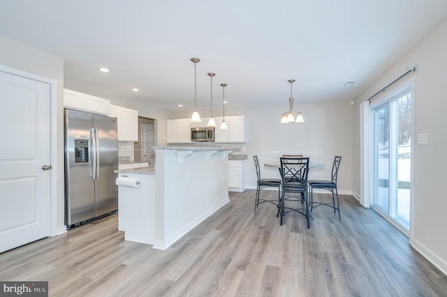 kitchen with decorative light fixtures, tasteful backsplash, a kitchen island, appliances with stainless steel finishes, and white cabinets