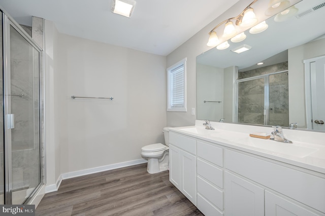 bathroom with toilet, hardwood / wood-style flooring, a shower with door, and vanity