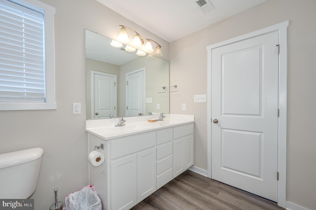 bathroom with wood-type flooring, toilet, and vanity