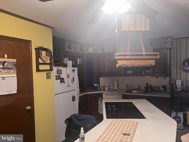 kitchen with tasteful backsplash, dark brown cabinets, sink, and white refrigerator