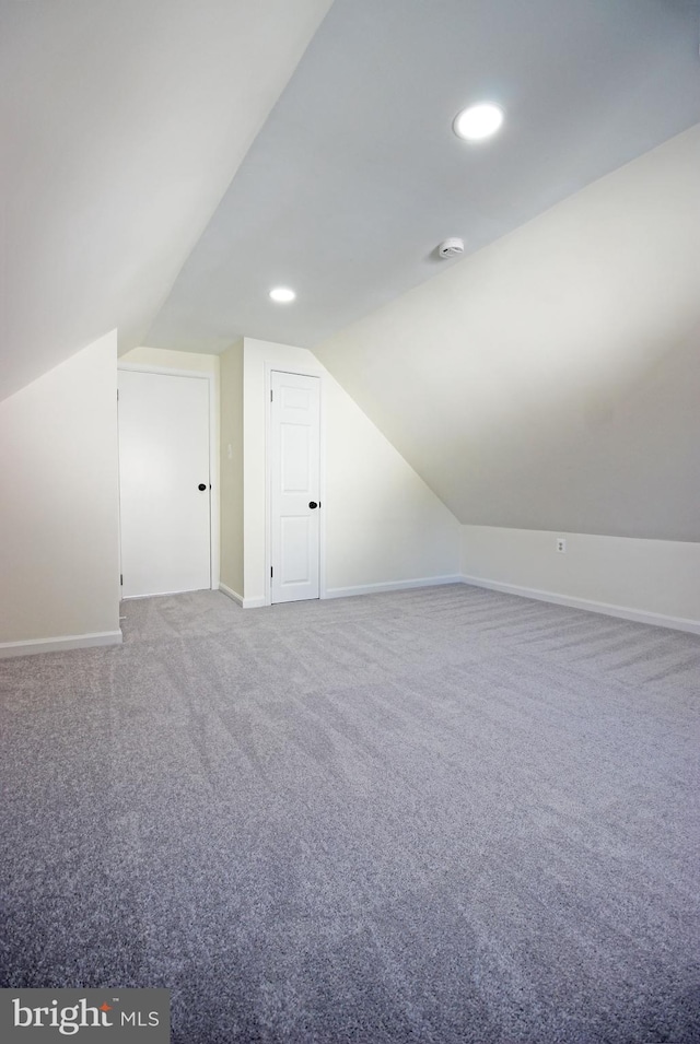 additional living space featuring vaulted ceiling and carpet flooring