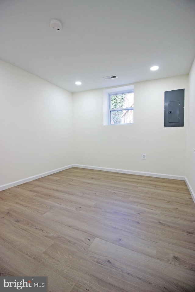 basement with electric panel and light hardwood / wood-style flooring