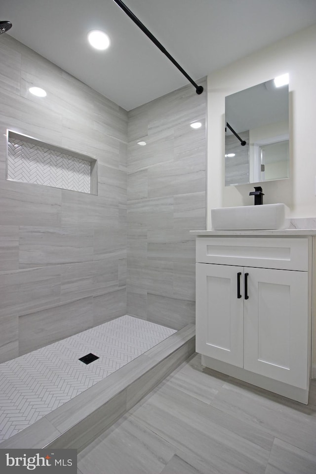 bathroom with a tile shower and vanity