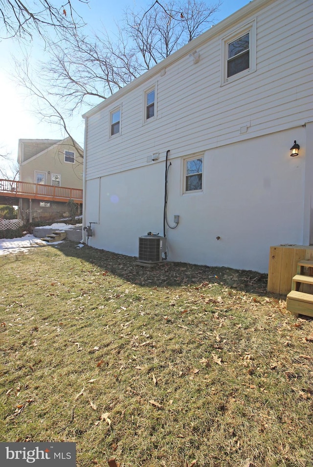 rear view of house with central AC and a lawn