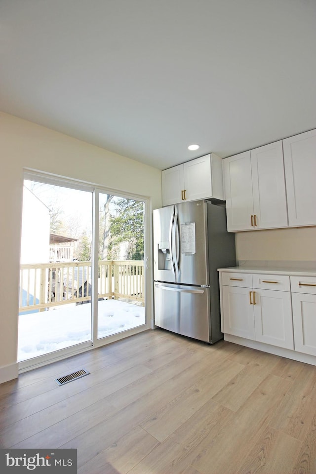 kitchen with light hardwood / wood-style floors, white cabinets, and stainless steel fridge