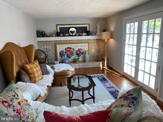 living room with french doors, a textured ceiling, and hardwood / wood-style floors