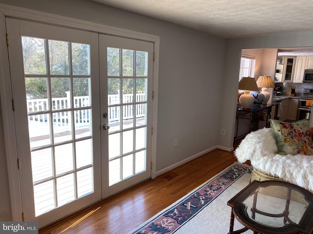 doorway to outside featuring a textured ceiling, hardwood / wood-style flooring, and french doors