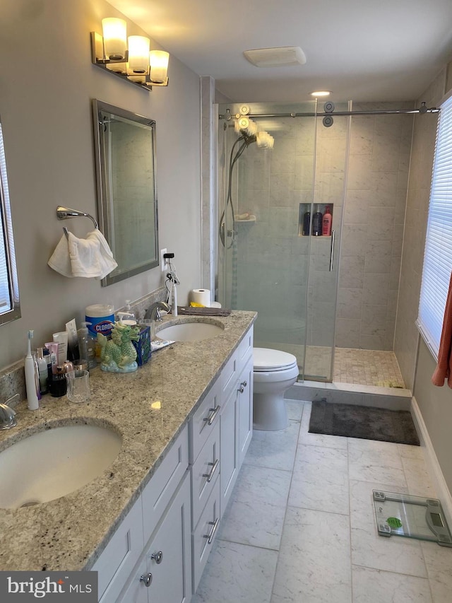 bathroom featuring toilet, vanity, and a shower with door