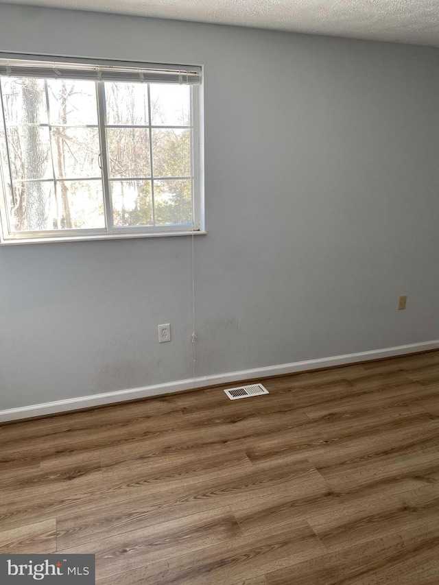 empty room with a textured ceiling and hardwood / wood-style floors