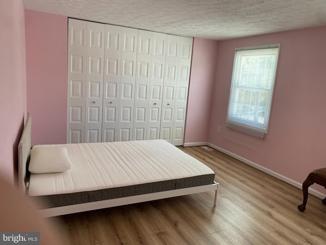 bedroom with a textured ceiling and hardwood / wood-style flooring