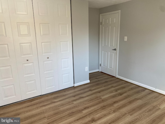 unfurnished bedroom with dark hardwood / wood-style floors and a closet