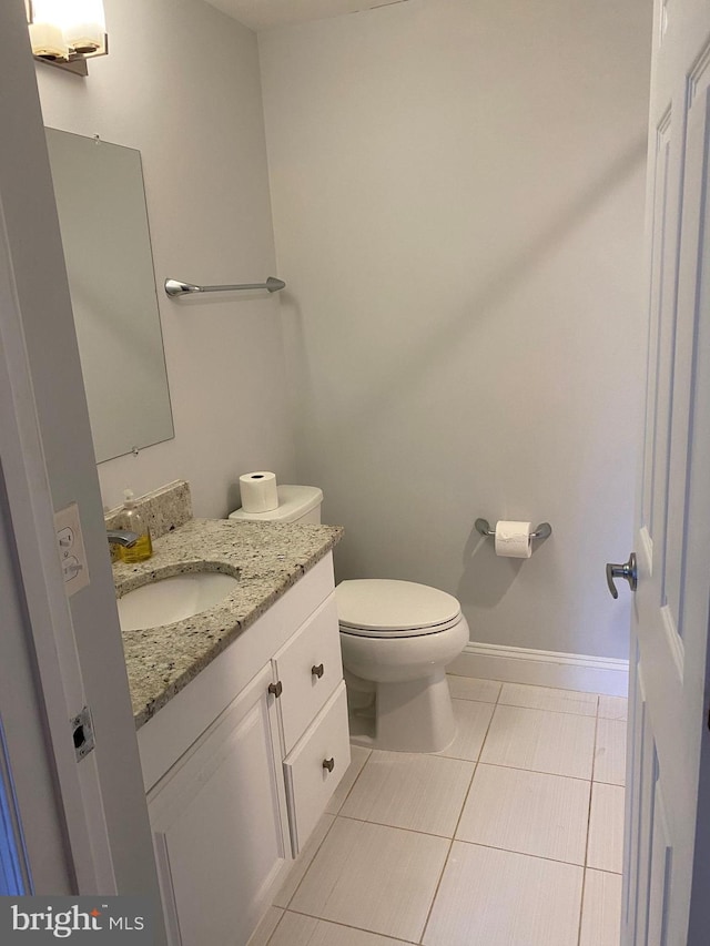 bathroom with toilet, vanity, and tile patterned flooring