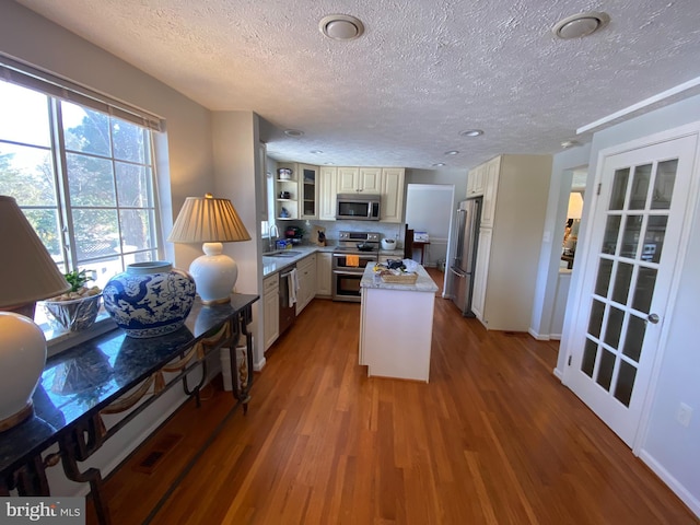 kitchen with a kitchen island, wood-type flooring, sink, appliances with stainless steel finishes, and white cabinets