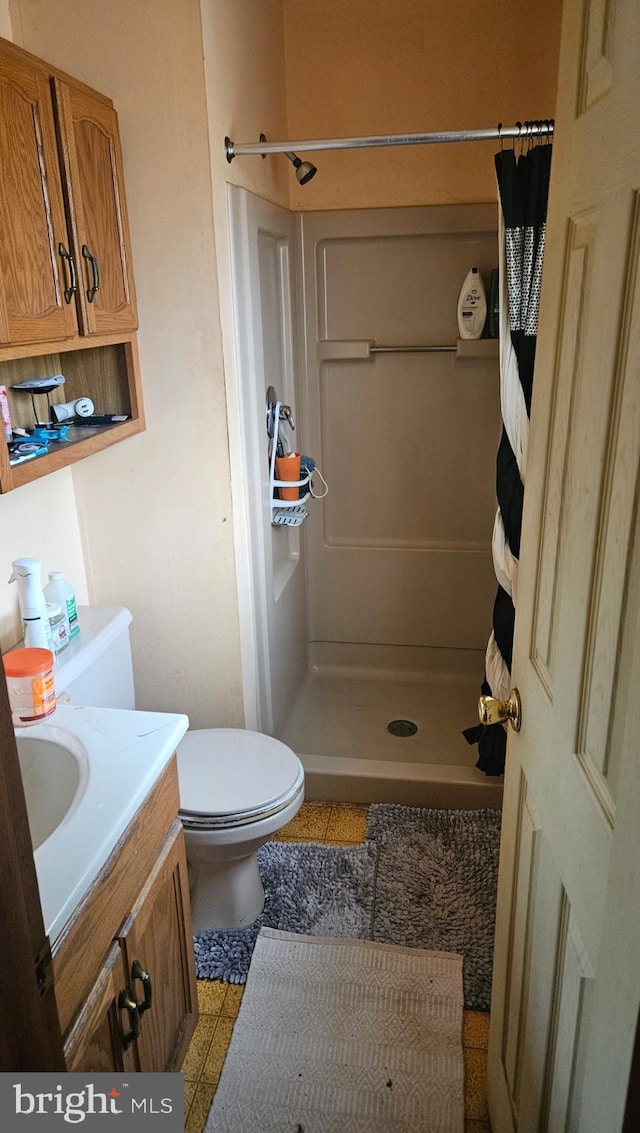 bathroom featuring vanity, tile patterned flooring, toilet, and walk in shower