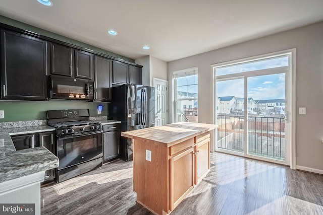 kitchen featuring butcher block countertops, black appliances, a center island, and light wood-type flooring