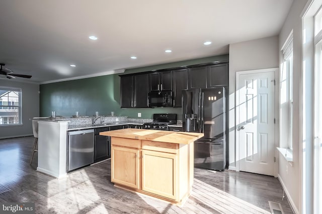 kitchen featuring black appliances, wooden counters, a kitchen island, wood-type flooring, and ceiling fan