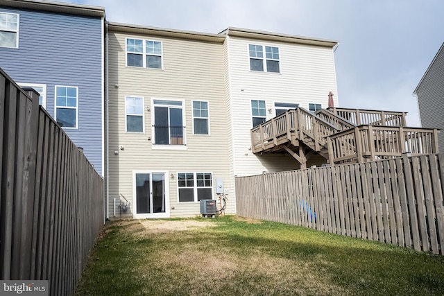 rear view of property with a deck, cooling unit, and a lawn