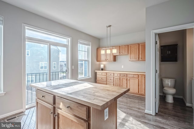 kitchen featuring light brown cabinets, wood counters, pendant lighting, and a center island