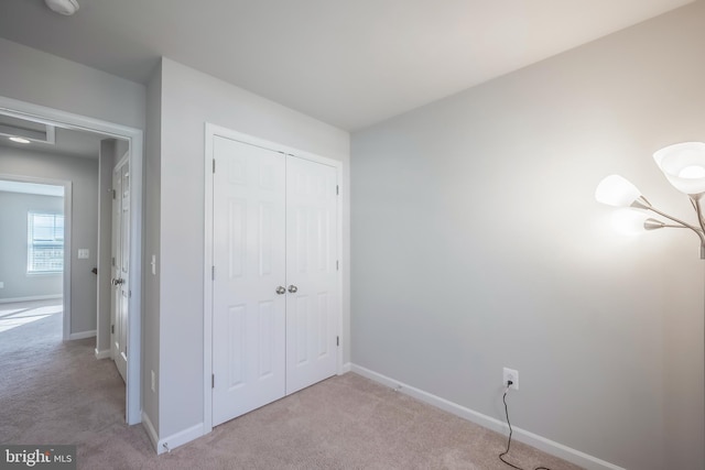 unfurnished bedroom featuring light colored carpet and a closet