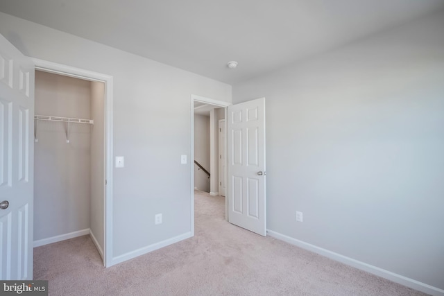 unfurnished bedroom with light colored carpet and a closet