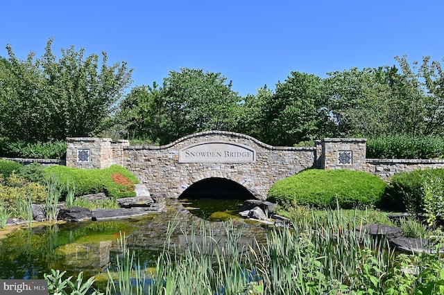 community / neighborhood sign with a small pond