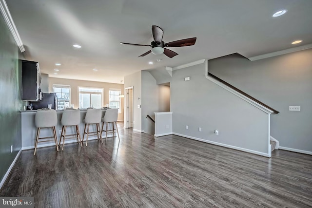 living room featuring ceiling fan, dark wood-type flooring, and crown molding